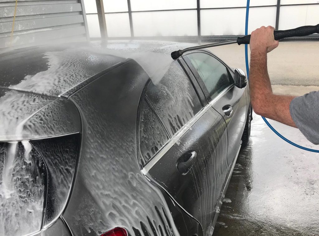 Un homme nettoie sa Mercédès classe A 200 grise avec une lance haute pression dans une station de lavage dans le Finistère